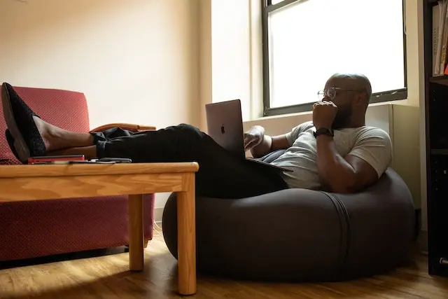 یک اقا در حال کار با لپ تاپ که روی مبلی راحت نشسته است . استفاده از مبلمان راحت میتواند فضای کاری مطلوب را به کارکنان هدیه دهد