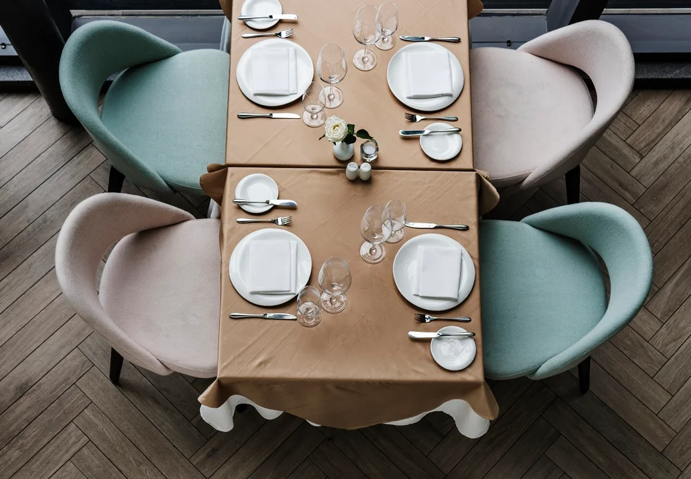میز نهارخوری که شامل چهار صندلی میباشد و ظروف غذا خوری از جمله بشقاب و قاشق و چنگال در سر میز قرار دارد