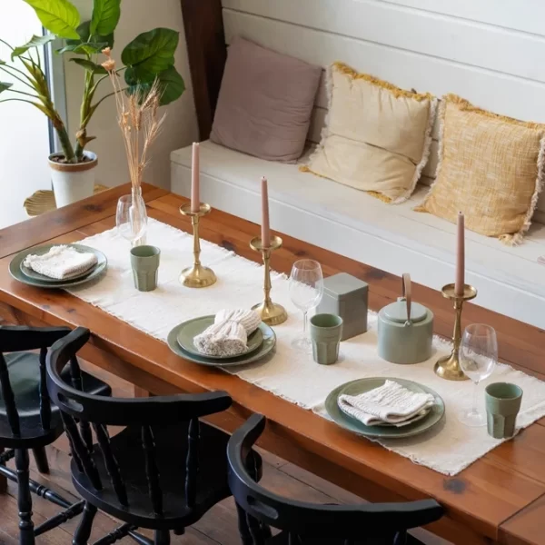 میز نهارخوری که شامل سه صندلی میباشد و ظروف غذا خوری از جمله بشقاب و قاشق و چنگال در سر میز قرار دارد و شمع نیز در سر میز برای زیبایی قرار دارد