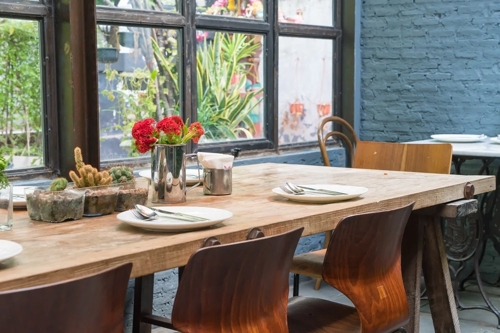 میز نهارخوری که شامل سه صندلی میباشد و ظروف غذا خوری از جمله بشقاب و قاشق و چنگال در سر میز قرار دارد و گل کاکتوس نیز در سر میز برای زیبایی قرار دارد . پنجره ها هم برای نور بیشتر و زیبا تر در کنار میز طراحی شده است