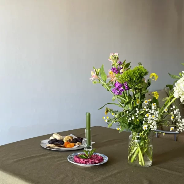 میزی که رو میزی آن سبز تیره میباشد و بر روی ان گلدان و بشقاب گذاشته شده است