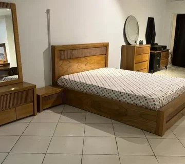 نمایشگاهی که ست اتاق خوابی چوبی که شامل تخت دو نفره و آیینه و کمد میشود قرار دارد