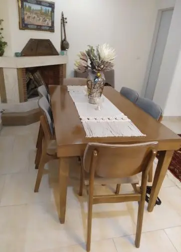 میز ناهار خوری 6 نفره چوبی که صندلی ها نیز در اطرافش قرار دارد